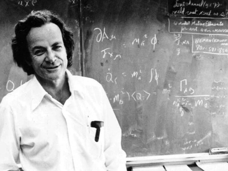 richard feynman standing in front of a blackboard