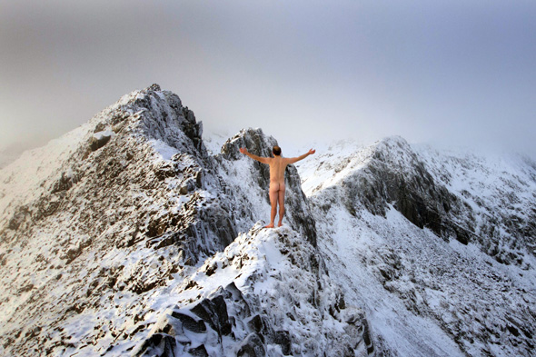 naked man standing on snow-covered mountain