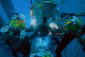 two divers welding a pipe underwater